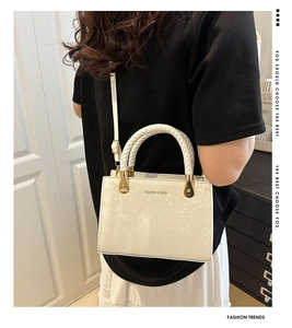 Detailed view of white faux leather crossbody bag with snake texture and woven handle