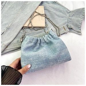 Detail of light blue denim bucket bag with sparkling rhinestones and silver chain strap