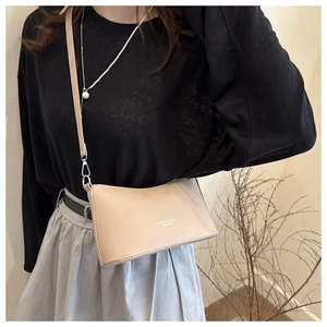 Detail view of beige leather half-moon bucket bag with elegant shoulder strap for women