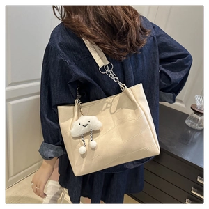 Detailed view of cream-white tote bag with quilted texture and plush cloud charm