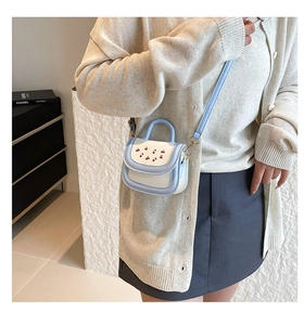 Detailed view of mini crossbody bag with cherry embroidery and gold hardware