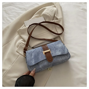Détail du sac baguette bleu mat avec bandoulière caramel et boucle dorée élégante