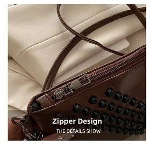 Detail of dark brown leather clutch with black rivets and smooth silver zipper closure
