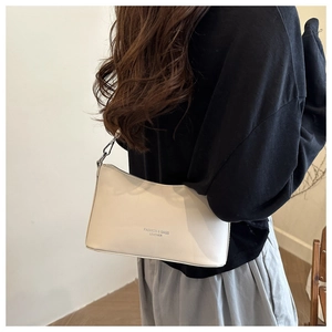 Close-up of cream leather bucket bag featuring silver hardware and embossed fashion logo