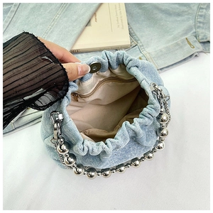 Close-up showing the interior lining and silver ball chain of the denim bucket bag