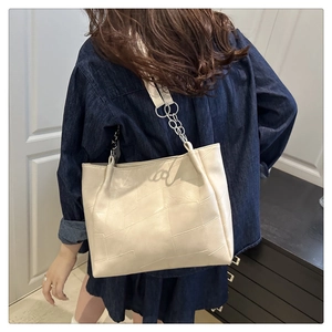 Detail of cream tote bag featuring geometric quilted stitching and stylish chain straps