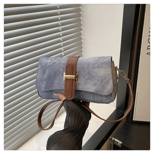 Détail du sac baguette en denim bleu avec sangle en cuir marron et boucle en H dorée