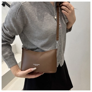 Close-up of brown leather bucket bag featuring silver hardware and fashion text details