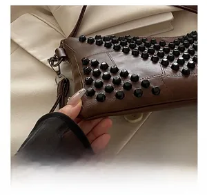 Macro detail of dark brown leather handbag with black rivet studs and block stitching