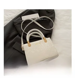 Close-up of cream white handbag featuring snake pattern texture and woven rope handle details