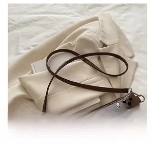 Detail view of dark brown leather envelope bag with rivets and adjustable shoulder strap