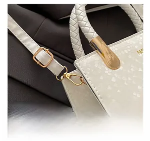 Detailed macro view of white faux snakeskin bag with gold hardware and woven handle