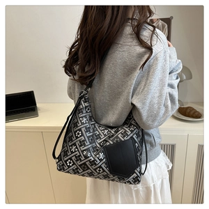 Detail of a chic tote bag with geometric patterns, white flowers, and a black front pocket