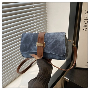 Détail du sac baguette en denim bleu avec sangle en cuir marron et boucle H dorée