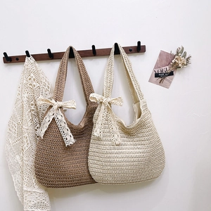 Handmade crochet woven tote bags with lace bows hanging on a minimal wall display