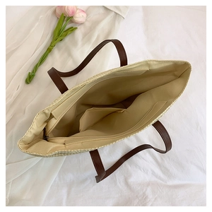 Close-up of woven tote bag interior with zipper compartment and brown leather handles