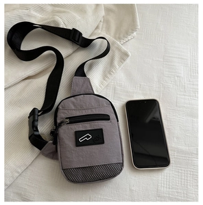 Vista dall'alto di una borsa a tracolla in nylon grigio accanto a uno smartphone per misura