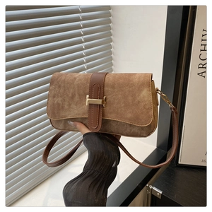 Détail du sac baguette en daim marron avec une boucle dorée en forme de H sur le devant