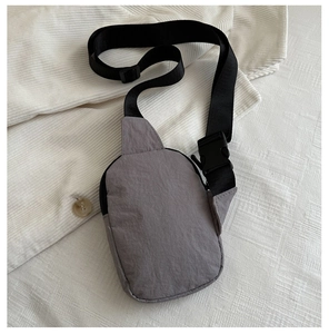 Dettaglio di una borsa a tracolla in nylon grigio con cinturino regolabile e fibbia nera