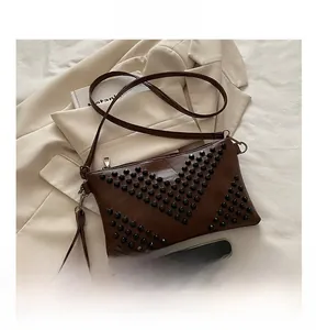Detail view of dark brown rivet envelope bag with size comparison to a smartphone