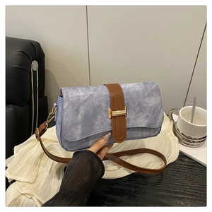 Détail du sac baguette en jean bleu clair avec bandoulière cuir marron et boucle or