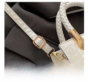 Detail showing the adjustable thin shoulder strap and white woven handle of the crossbody bag