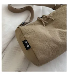 Detailed macro view of khaki nylon fabric texture and brand label on a shoulder bag