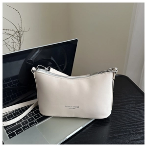 Detail of a beige leather bucket bag with silver zipper and logo near a laptop