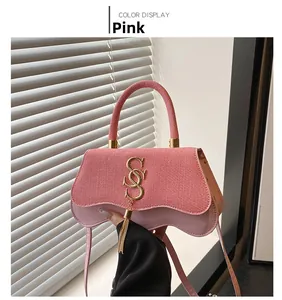 Détail du rabat rose tressé et du logo S doré avec pompons sur le petit sac à bandoulière