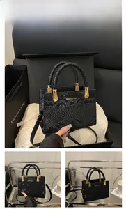 Detailed view of a black stone-textured handbag with gold hardware and branding labels