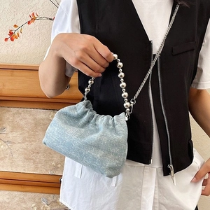 Light blue denim bucket bag featuring silver sphere handle and stylish chain strap