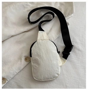 Dettaglio borsa a tracolla in nylon crema con cinturino nero regolabile su velluto