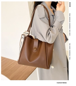 Detail of dark brown leather tote bag with elegant printed scarf and metal bottom studs