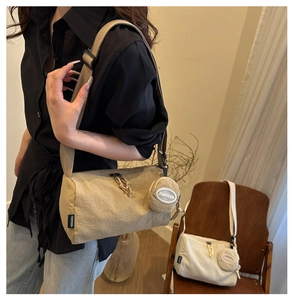 Detail of minimalist nylon cylindrical crossbody bag with a round hanging coin purse