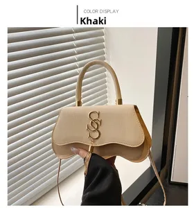 Détail du sac bandoulière kaki avec rabat tressé et pompon doré en métal