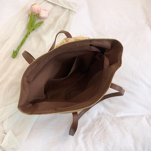 Large woven straw tote bag with brown leather handles and spacious interior compartments