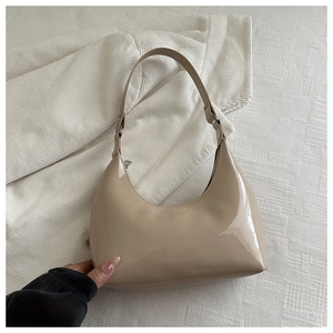 Détail du sac lune en cuir verni beige brillant avec fermeture éclair et bandoulière courbe