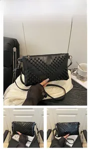 Detail of black matte rivet envelope bag with metallic studs in V-shape arrangement