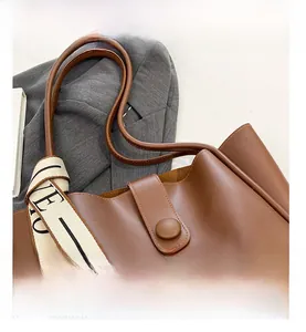 Detail of brown faux leather tote bag with flap closure and logo canvas strap