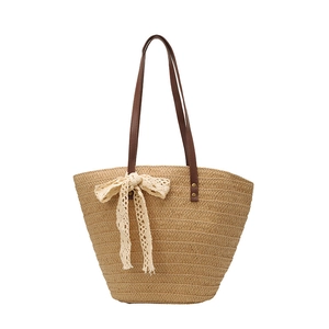 Handwoven straw tote bag with cream lace bow and dark brown leather shoulder straps