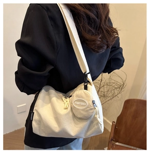 Detail of minimalist beige canvas shoulder bag with small round coin purse and logo tag