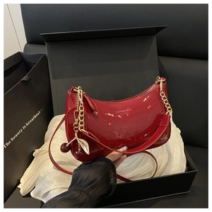 Détail du sac d'épaule en cuir verni rouge avec breloque cerise et zip doré