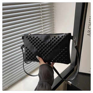 Detail of black envelope clutch with 3D cylindrical studs in a geometric star pattern
