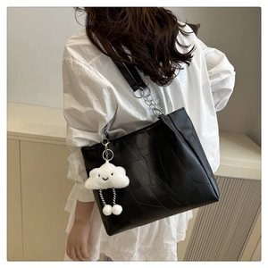 Detail of black patchwork tote bag with cute cloud plush charm on a model