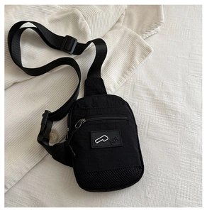 Dettaglio borsa a tracolla in nylon nero con scomparto a zip e tasca a rete su bianco