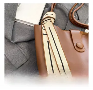 Close-up of brown tote bag side showing decorative cream ribbon with black lettering
