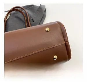 Detail view of brown leather bag base showing gold protective metal studs and stitching