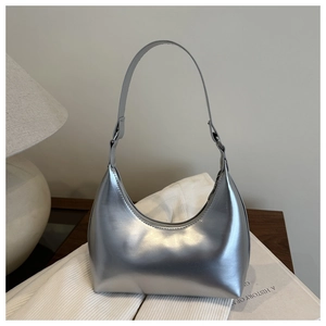 Sac hobo argenté en cuir verni métallisé posé sur un tissu en maille blanc élégant