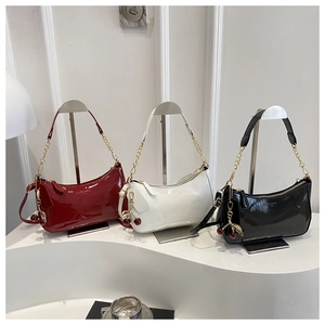 Detailed shot of three patent leather shoulder bags in red, white and black with cherry charm