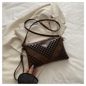 Close-up of brown PU envelope bag with black V-shaped rivet studs and crossbody strap